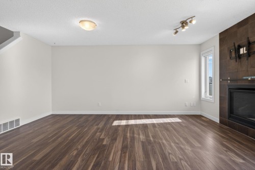 Spacious interior featuring wood-finish flooring, a tile-surround fireplace, a large window, and recessed lighting fixtures - 5306 67 Street E, Beaumont, AB 