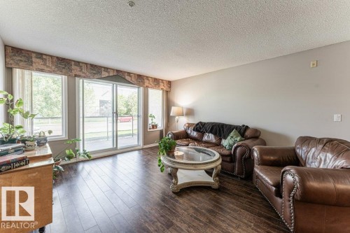 Spacious living area featuring rich wood-finish flooring - 101 10421 42 Avenue, Edmonton, AB 
