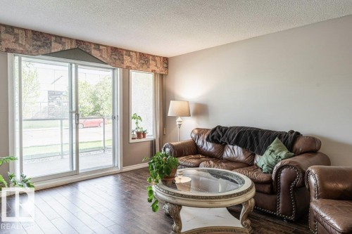Living area featuring dark wood-finish flooring and neutral wall tones - 101 10421 42 Avenue, Edmonton, AB 