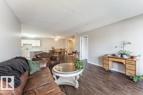 Open-concept living space featuring wood-finish flooring, light gray walls, and textured ceilings - 101 10421 42 Avenue, Edmonton, AB 