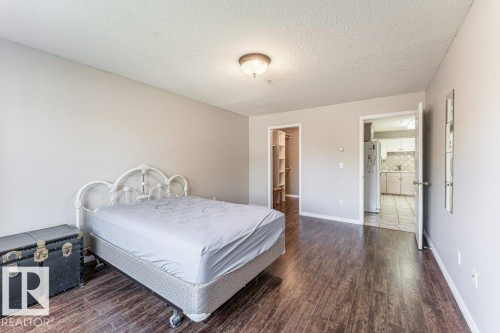 Spacious room featuring wood-finish flooring, a neutral color palette, and a ceiling-mounted light fixture - 101 10421 42 Avenue, Edmonton, AB 