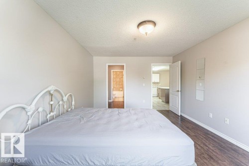 Bedroom featuring wood-finish flooring, neutral wall paint, and a semi-flush mount ceiling light - 101 10421 42 Avenue, Edmonton, AB 