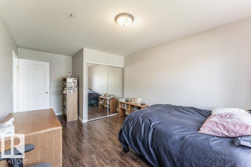Interior room featuring wood-finish flooring and a white paneled door - 101 10421 42 Avenue, Edmonton, AB 