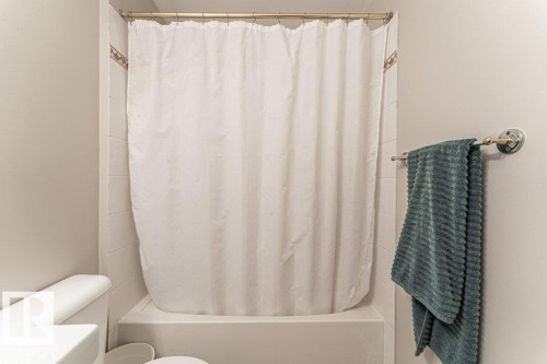 White bathtub and shower combination with white tile surround - 101 10421 42 Avenue, Edmonton, AB 