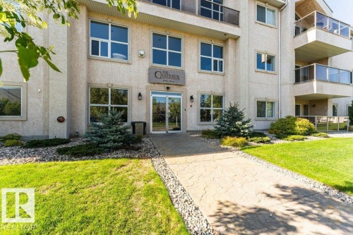 Stucco exterior building entrance featuring a stone pathway bordered by decorative rock landscaping - 101 10421 42 Avenue, Edmonton, AB 