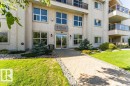 Stucco exterior building entrance featuring a stone pathway bordered by decorative rock landscaping - 101 10421 42 Avenue, Edmonton, AB 