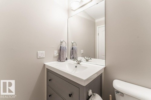 Vanity with integrated sink, rectangular mirror, and overhead lighting fixture - 101 10421 42 Avenue, Edmonton, AB 