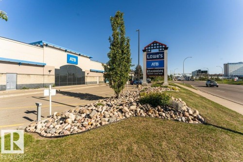 Commercial building with a neutral facade and blue trim, featuring extensive paved parking - 101 10421 42 Avenue, Edmonton, AB 