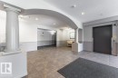 Building lobby featuring tiled flooring, architectural columns, an arched doorway, recessed lighting, and paneling along the walls - 101 10421 42 Avenue, Edmonton, AB 
