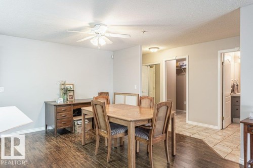 Open-concept dining area featuring wood-finish flooring, a ceiling fan with integrated lighting, and neutral wall tones - 101 10421 42 Avenue, Edmonton, AB 