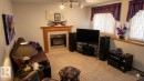 Carpeted living area featuring a fireplace with a wood mantel and tile surround - 1188 Joyce Road Nw, Edmonton, AB 
