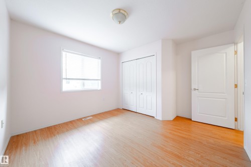 Bright room featuring wood-finish flooring, a white window frame with blinds, a bi-fold closet door, and a paneled interior door with silver hardware - 120 13320 124 Street Nw, Edmonton, AB 