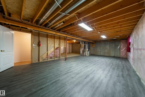Spacious lower level featuring contemporary wood-finish flooring, exposed ceiling joists, and visible utility infrastructure - 120 13320 124 Street Nw, Edmonton, AB 