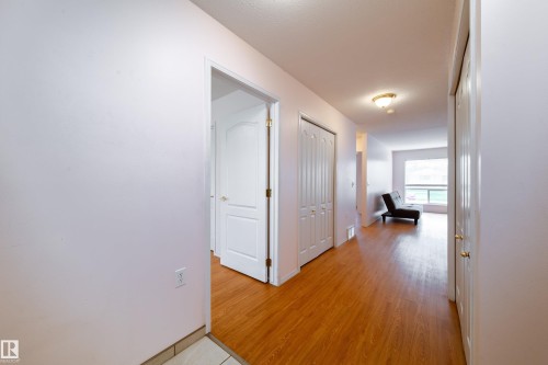 Entryway featuring wood-finish flooring, two white panel doors, and recessed lighting - 120 13320 124 Street Nw, Edmonton, AB 
