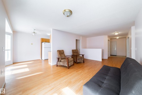 Open-concept living space featuring wood-finish flooring, white walls, and a ceiling-mounted light fixture - 120 13320 124 Street Nw, Edmonton, AB 