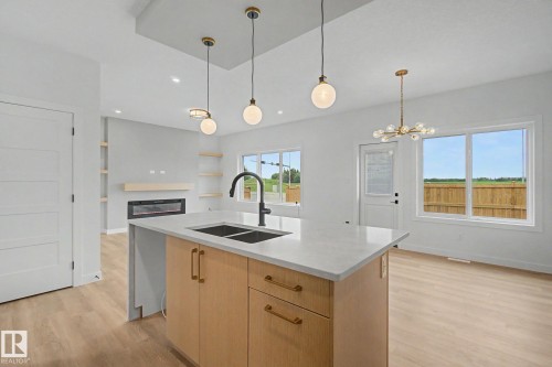 Kitchen island featuring a double sink, matte black faucet, light-toned cabinetry, and a light-toned countertop - 2 Willow Heights Drive, Stony Plain, AB 