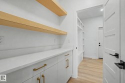 Built-in white cabinetry with gold-tone hardware, white countertops, and light wood-finish floating shelves - 