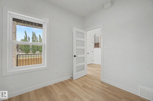 Room featuring wood-finish flooring, white walls, and a modern five-panel door with frosted glass inserts - 2 Willow Heights Drive, Stony Plain, AB 