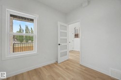 Room featuring wood-finish flooring, white walls, and a modern five-panel door with frosted glass inserts - 