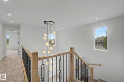 Modern multi-level chandelier illuminating a staircase with wood newel posts and black metal balusters - 