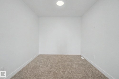 Recessed ceiling light illuminating a room with neutral-toned carpeting, white walls, and white baseboards - 2 Willow Heights Drive, Stony Plain, AB 