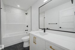Bathroom featuring a single vanity with a white countertop, undermount sink, and matte black faucet - 