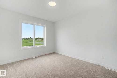 Bright interior room featuring a large window, neutral carpeting, white baseboards, a flush-mount ceiling light, and white walls - 2 Willow Heights Drive, Stony Plain, AB 