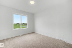 Bright interior room featuring a large window, neutral carpeting, white baseboards, a flush-mount ceiling light, and white walls - 