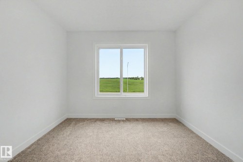 Room featuring neutral tone carpeting, white painted walls, white trim, and a white-framed window - 2 Willow Heights Drive, Stony Plain, AB 
