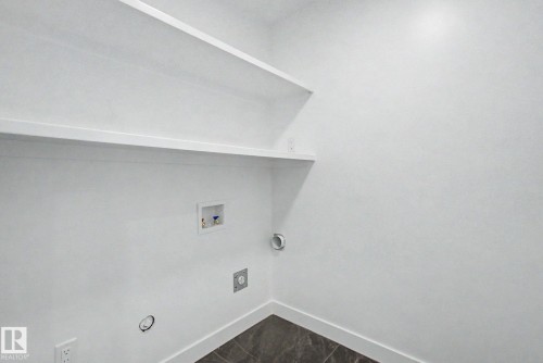 Utility area featuring built-in shelving, white walls, and a dark tile floor - 2 Willow Heights Drive, Stony Plain, AB 