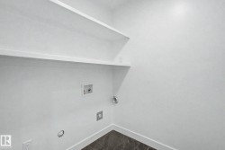 Utility area featuring built-in shelving, white walls, and a dark tile floor - 