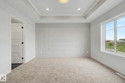 Spacious room featuring a decorative accent wall with panel molding, a recessed ceiling with crown molding, and recessed lighting - 2 Willow Heights Drive, Stony Plain, AB 