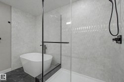 Freestanding soaking tub and glass-enclosed shower with matte black fixtures - 