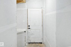 Two-panel interior door with square hardware, surrounded by drywall ready for finishing - 