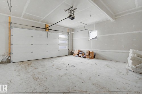 Spacious garage with a white sectional door featuring horizontal frosted glass panels - 2 Willow Heights Drive, Stony Plain, AB 