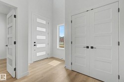 Entryway featuring a contemporary white door with frosted glass panels and matte black hardware - 
