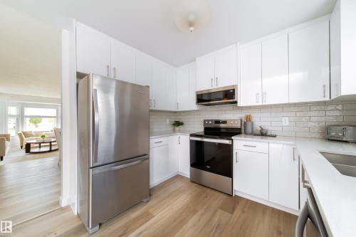 Modern kitchen with white cabinetry and light wood-finish flooring - 5607 188A Street, Edmonton, AB 