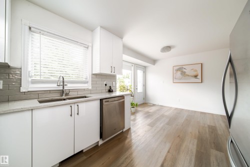 Contemporary kitchen featuring white cabinetry, light countertops, and a gray subway tile backsplash - 5607 188A Street, Edmonton, AB 