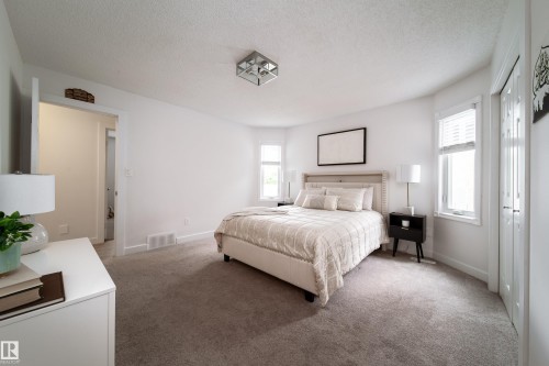 Carpeted bedroom featuring a neutral color palette, recessed window, bi-fold closet doors, and an overhead flush-mount light fixture - 5607 188A Street, Edmonton, AB 
