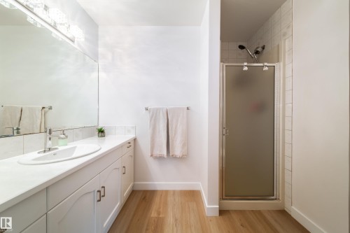 Bathroom featuring a white vanity with an integrated sink, polished chrome faucet, and expansive mirror - 5607 188A Street, Edmonton, AB 