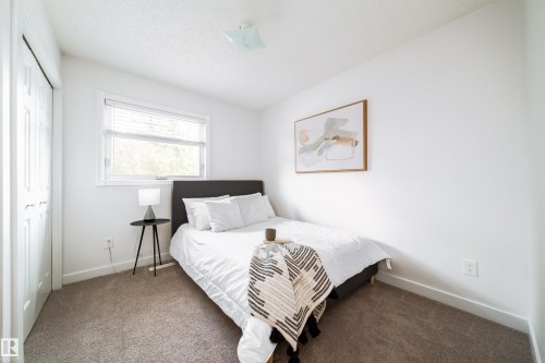 Carpeted room featuring a double-door closet, white walls, and a window with blinds - 5607 188A Street, Edmonton, AB 