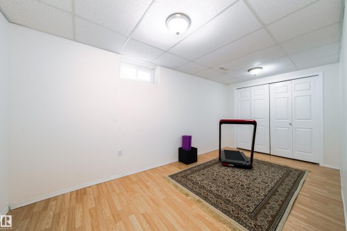 Spacious room featuring light wood-finish flooring, white walls, and a drop ceiling with integrated lighting - 5607 188A Street, Edmonton, AB 