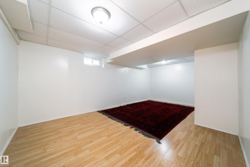 Finished room featuring wood-finish flooring, white walls, and a drop ceiling with recessed lighting - 5607 188A Street, Edmonton, AB 