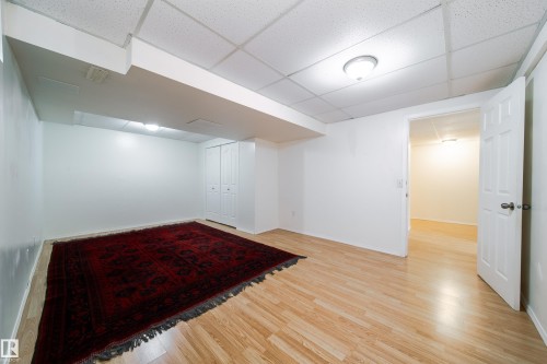 Light wood-finish flooring complements white walls and ceiling tiles - 5607 188A Street, Edmonton, AB 
