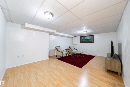 Spacious room featuring light wood-finish flooring, white walls, and a drop ceiling with integrated lighting - 5607 188A Street, Edmonton, AB 