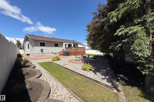 Expansive backyard featuring a multi-level deck, a brick patio, and a stone-lined garden area with decorative rock and lawn sections - 5607 188A Street, Edmonton, AB 