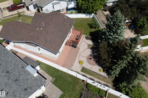 Expansive backyard featuring a multi-level paver patio, a wooden deck, and mature evergreen trees - 5607 188A Street, Edmonton, AB 