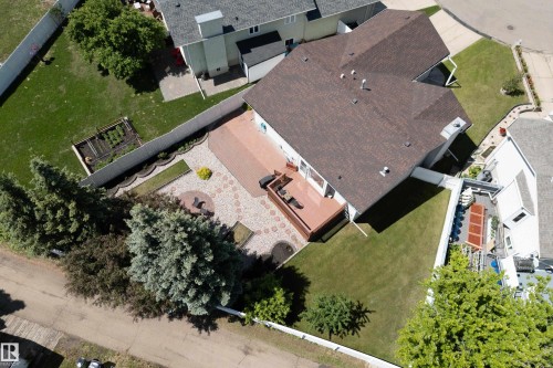 Expansive backyard featuring a multi-level composite deck, a large paver patio, a raised garden bed, mature trees, and a privacy fence - 5607 188A Street, Edmonton, AB 