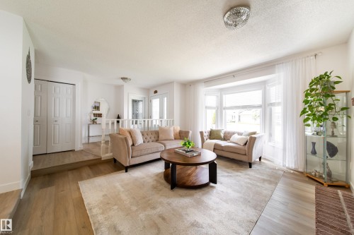 Bright living area with a prominent bay window and light-tone wood-finish flooring - 5607 188A Street, Edmonton, AB 