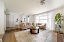Bright living area with a prominent bay window and light-tone wood-finish flooring - 5607 188A Street, Edmonton, AB 